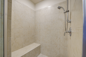 A shower area with a bench and a shower head.